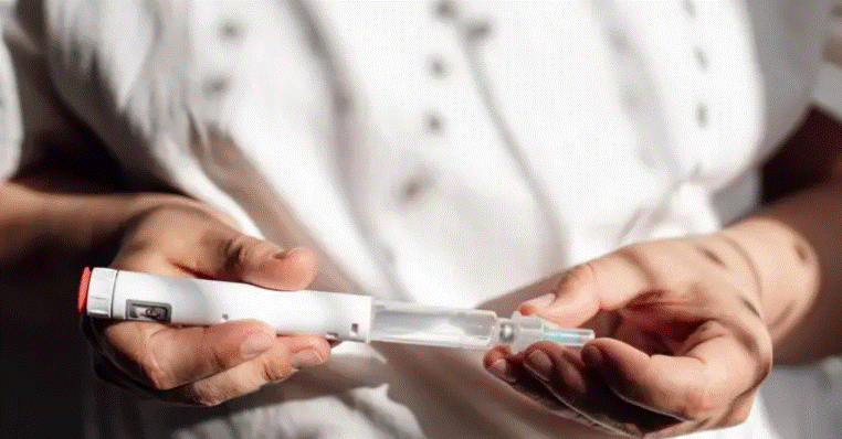 하얀색 셔츠를 입은 사람이 '위고비(Wegovy)' 주사 펜을 들고 사용 준비를 하는 모습